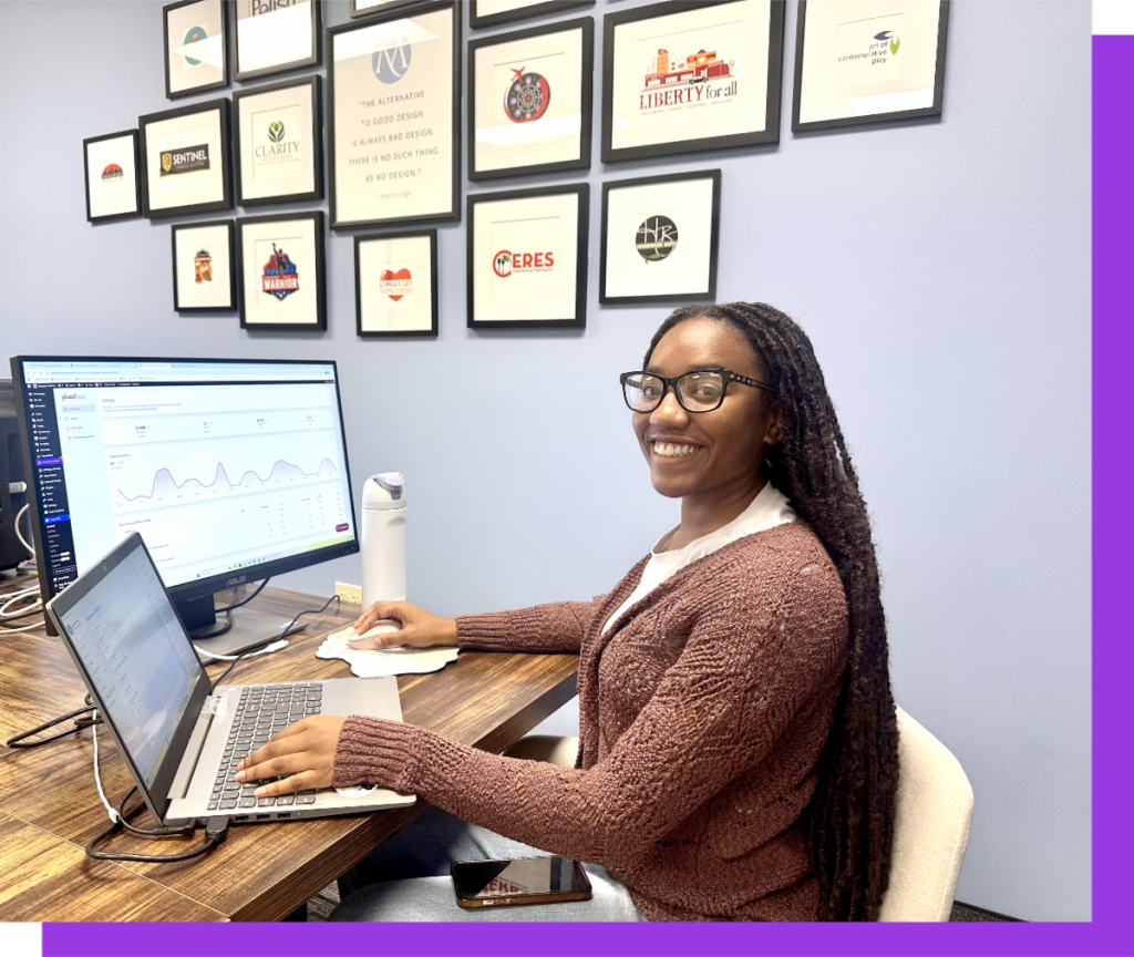 Kaila Anderson, Website SEO and AEO specialist sitting at her desk with two monitors